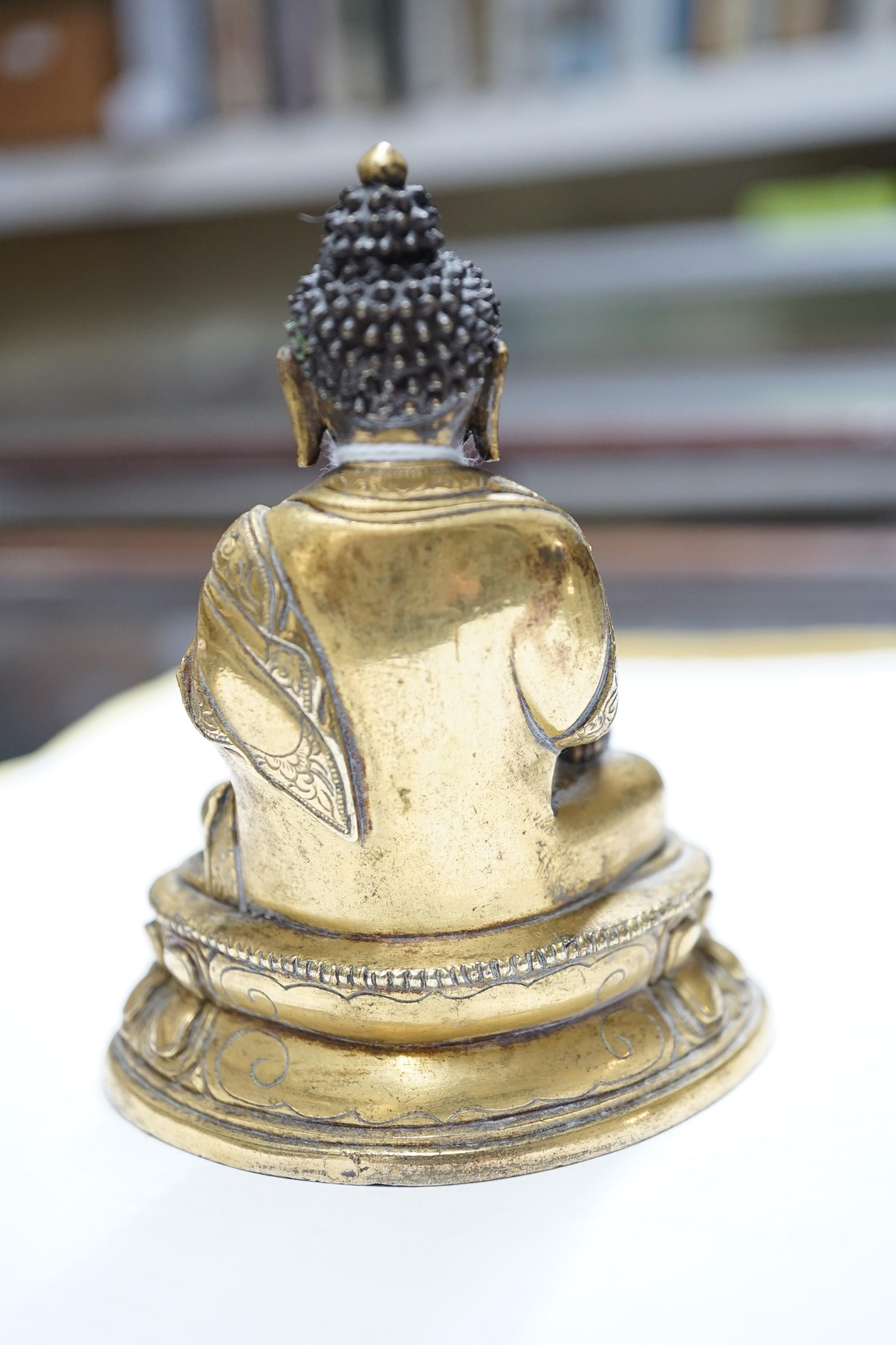 A small Tibetan gilt bronze seated figure of Buddha Shakyamuni, 18th century, 9.5cm high, lacking bowl in left hand